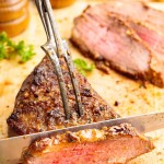 Slicing juicy oven-roasted Tri Tip Steak with a seared crust on a wooden cutting board.
