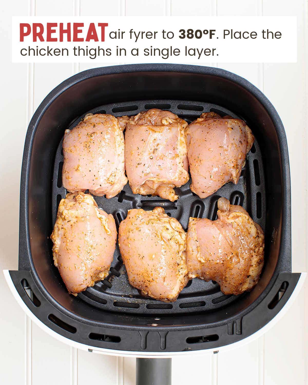 Six marinated chicken thighs in an air fryer.