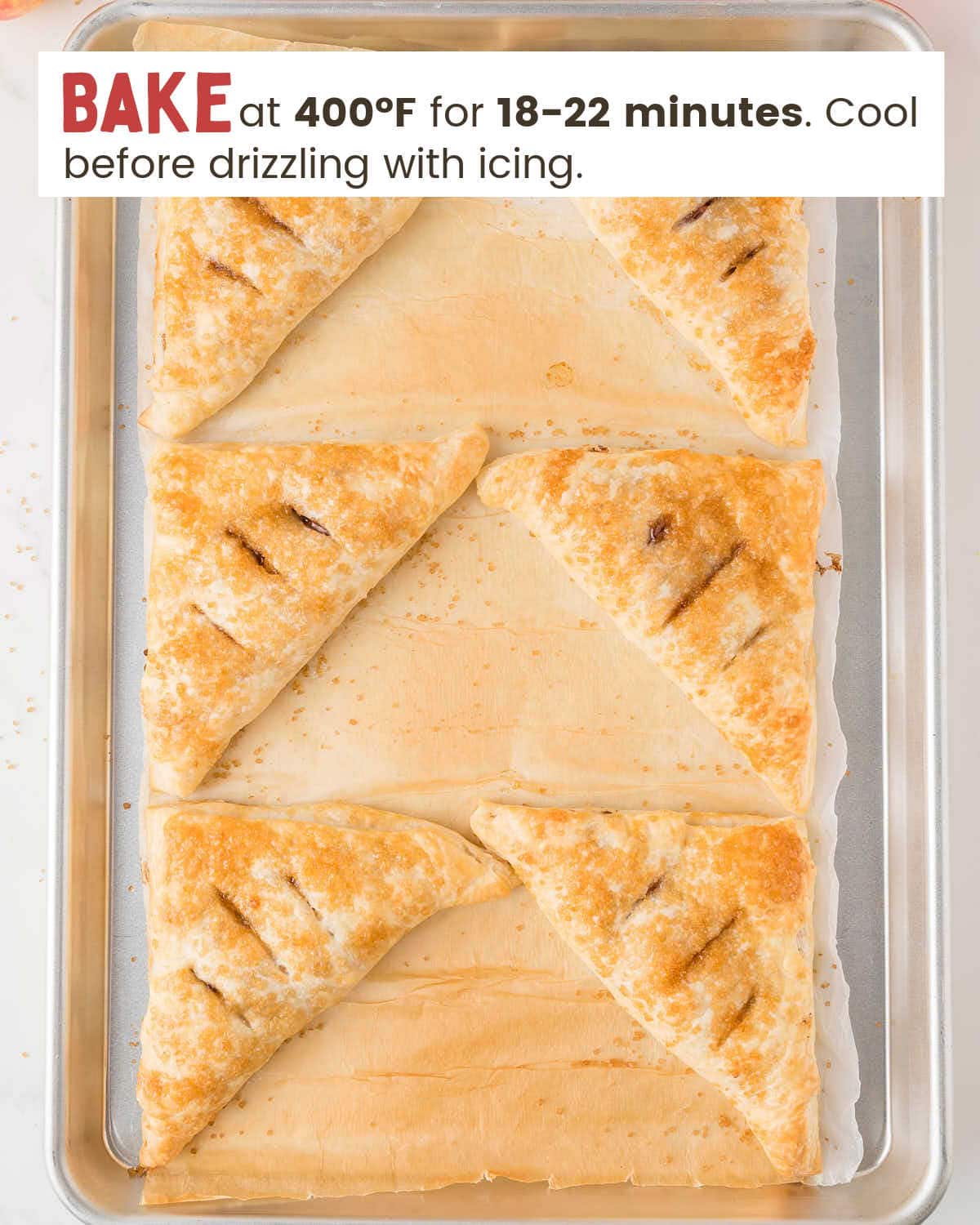 Baked apple turnovers on a baking tray.