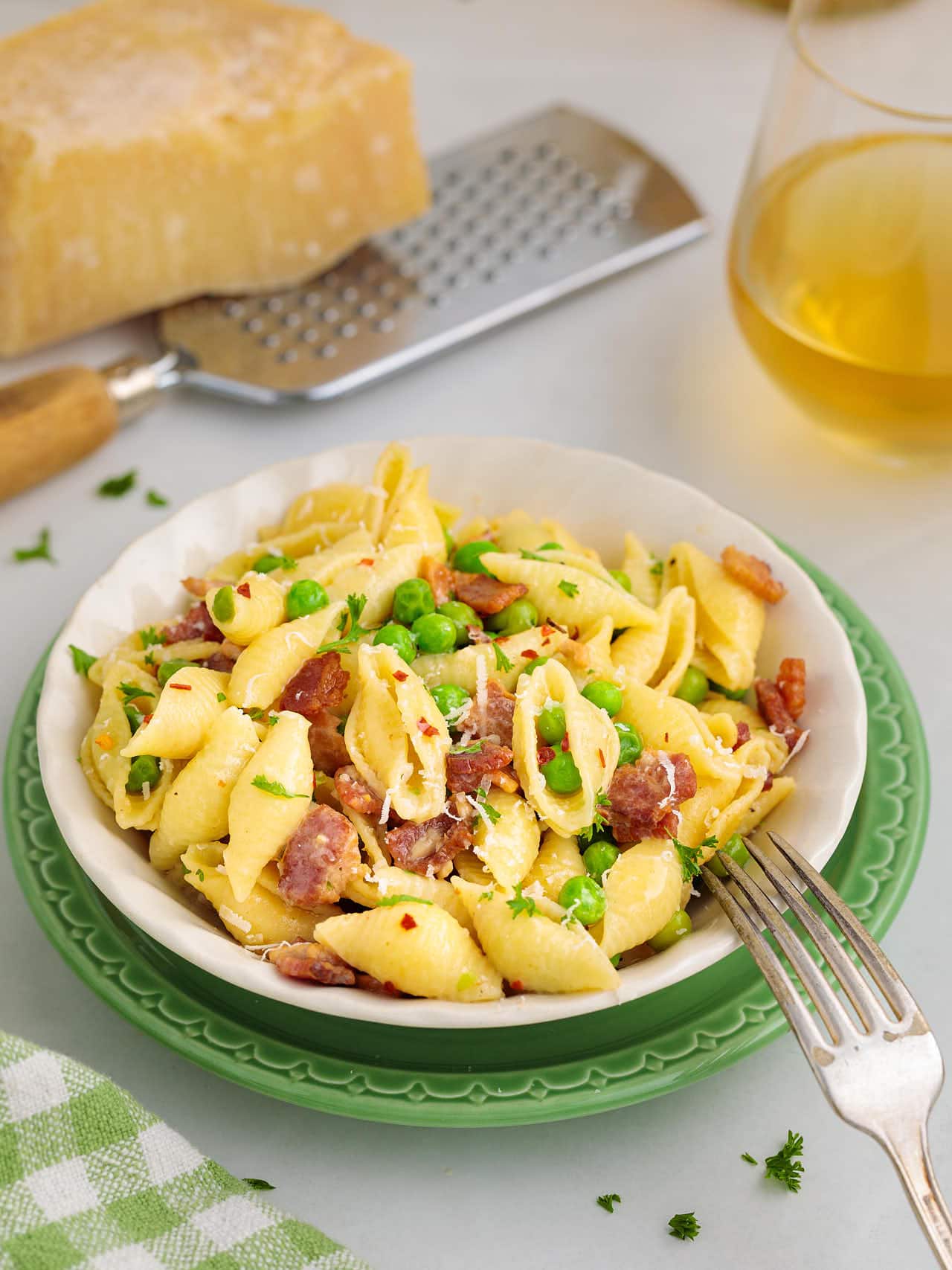 Bacon Pasta served in a white plate sitting on a green serving plate.