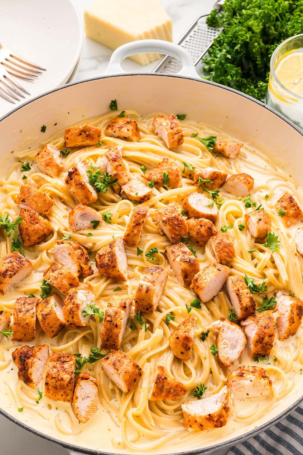A pan filled with Blackened Chicken Alfredo and pasta on a table.