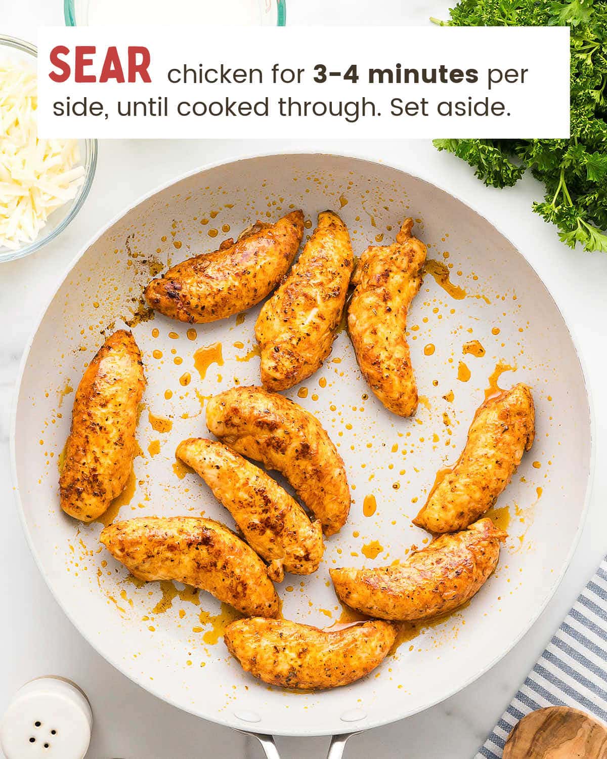 Seared blackened chicken tenders in a white skillet.