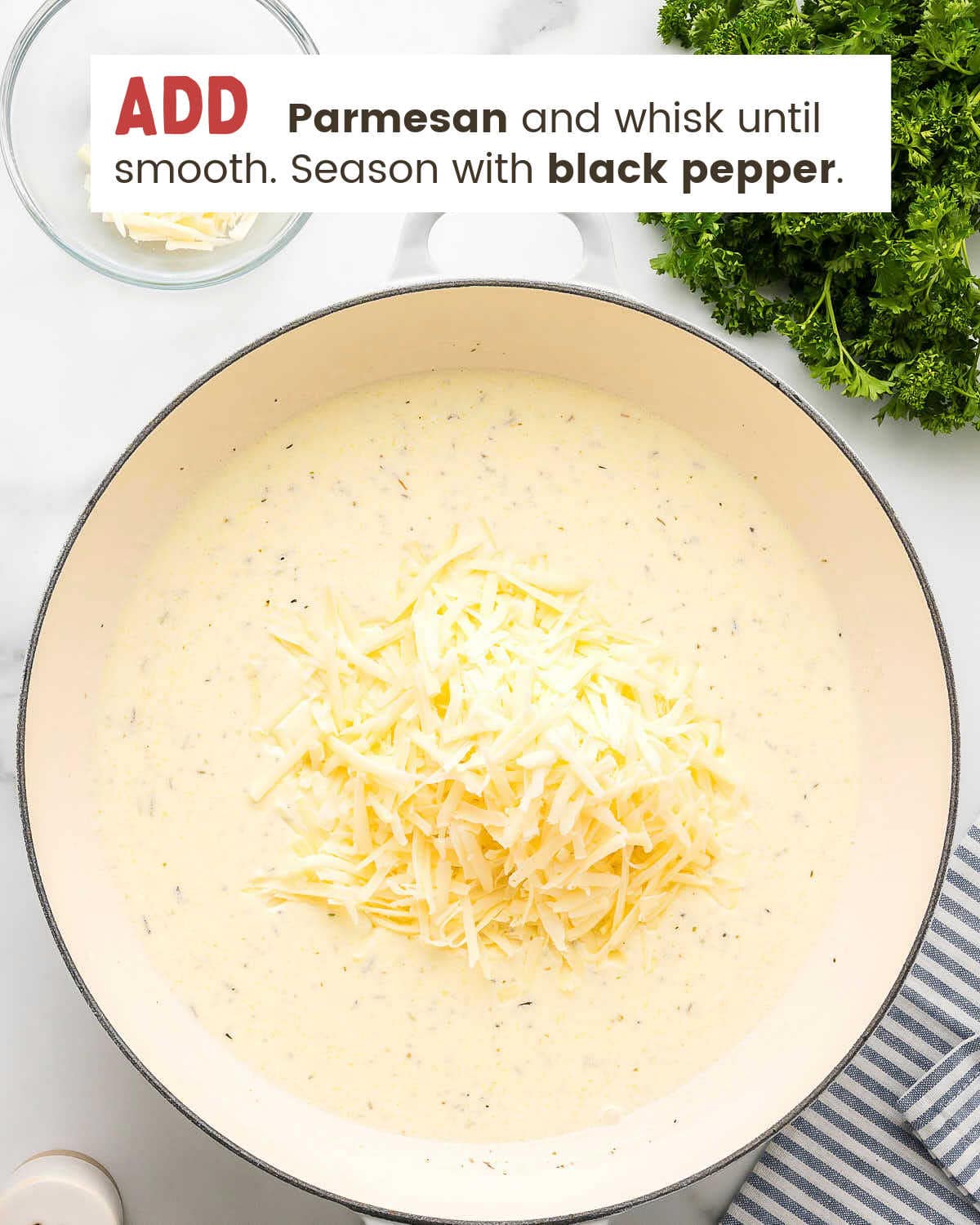 Shredded Parmesan added to the cream sauce in a large pan.