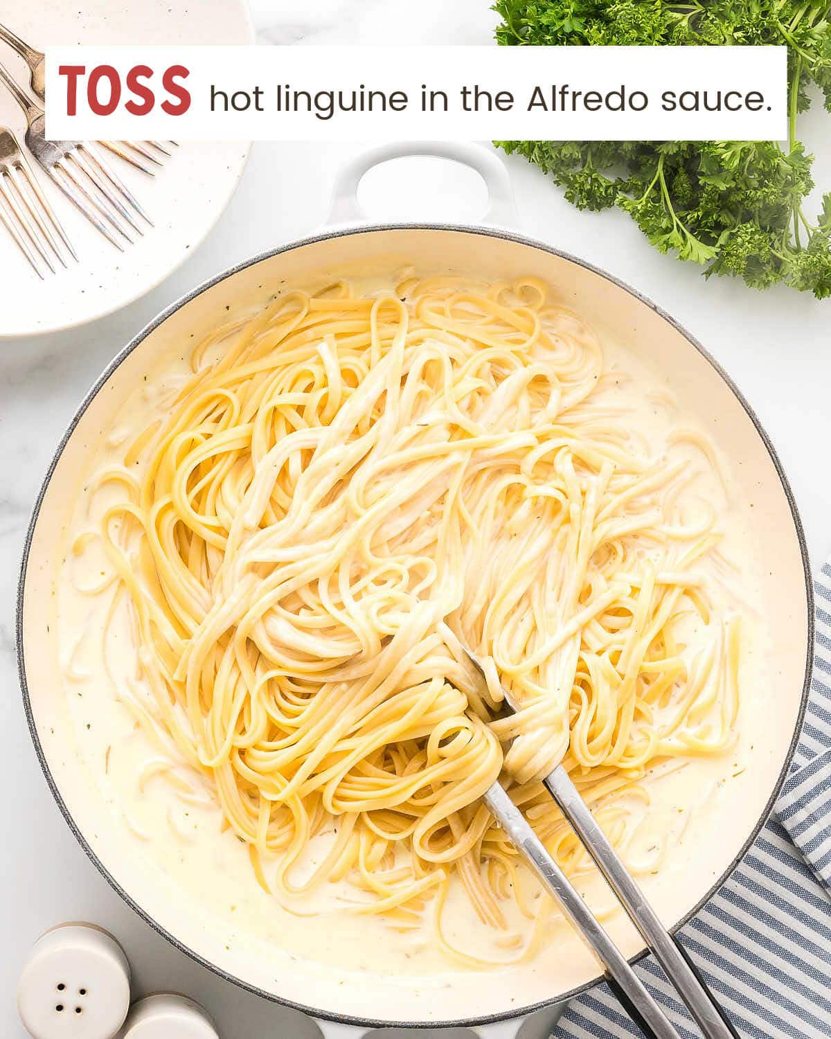 Shredded Parmesan added to the cream sauce in a large pan.