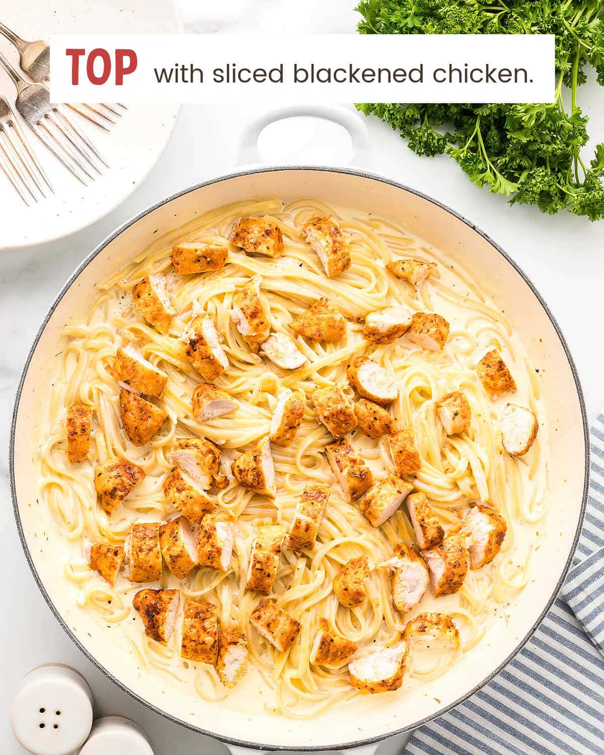 Cooked linguine tossed in homemade Alfredo sauce with tongs.