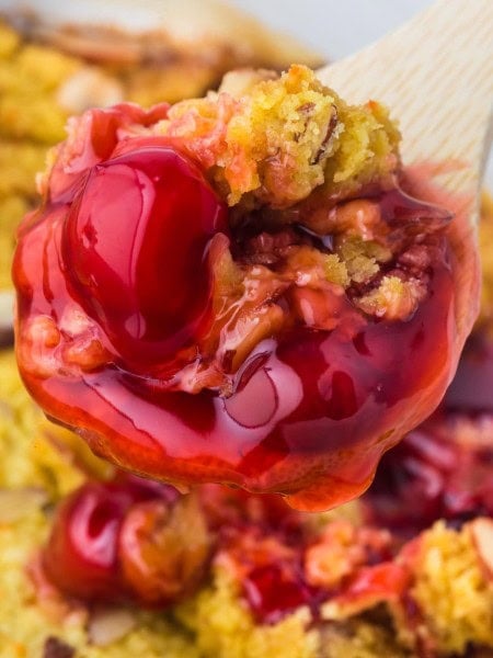 A spoon full of cherry pie is being held up.