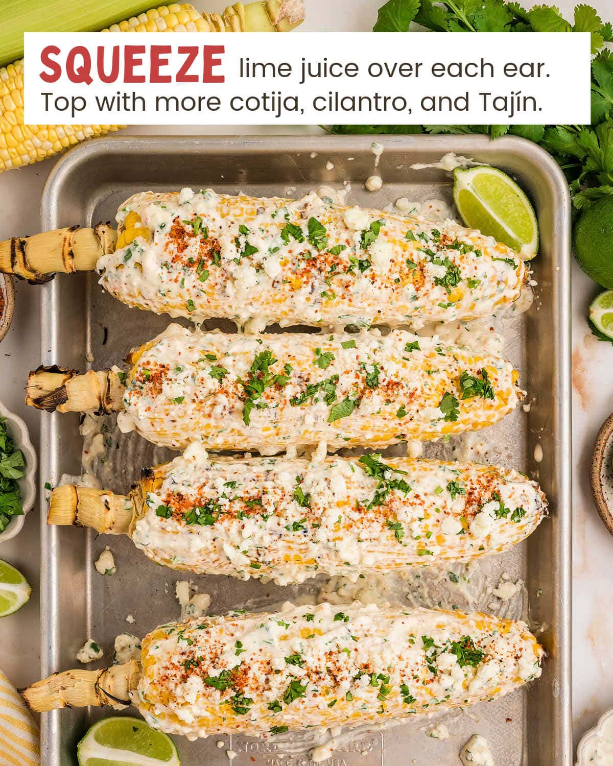 Four corn on the cob pieces on a tray covered with elote sauce.