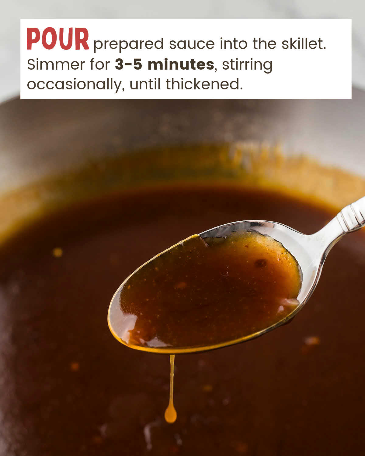 Orange chicken sauce on a spoon over a skillet.