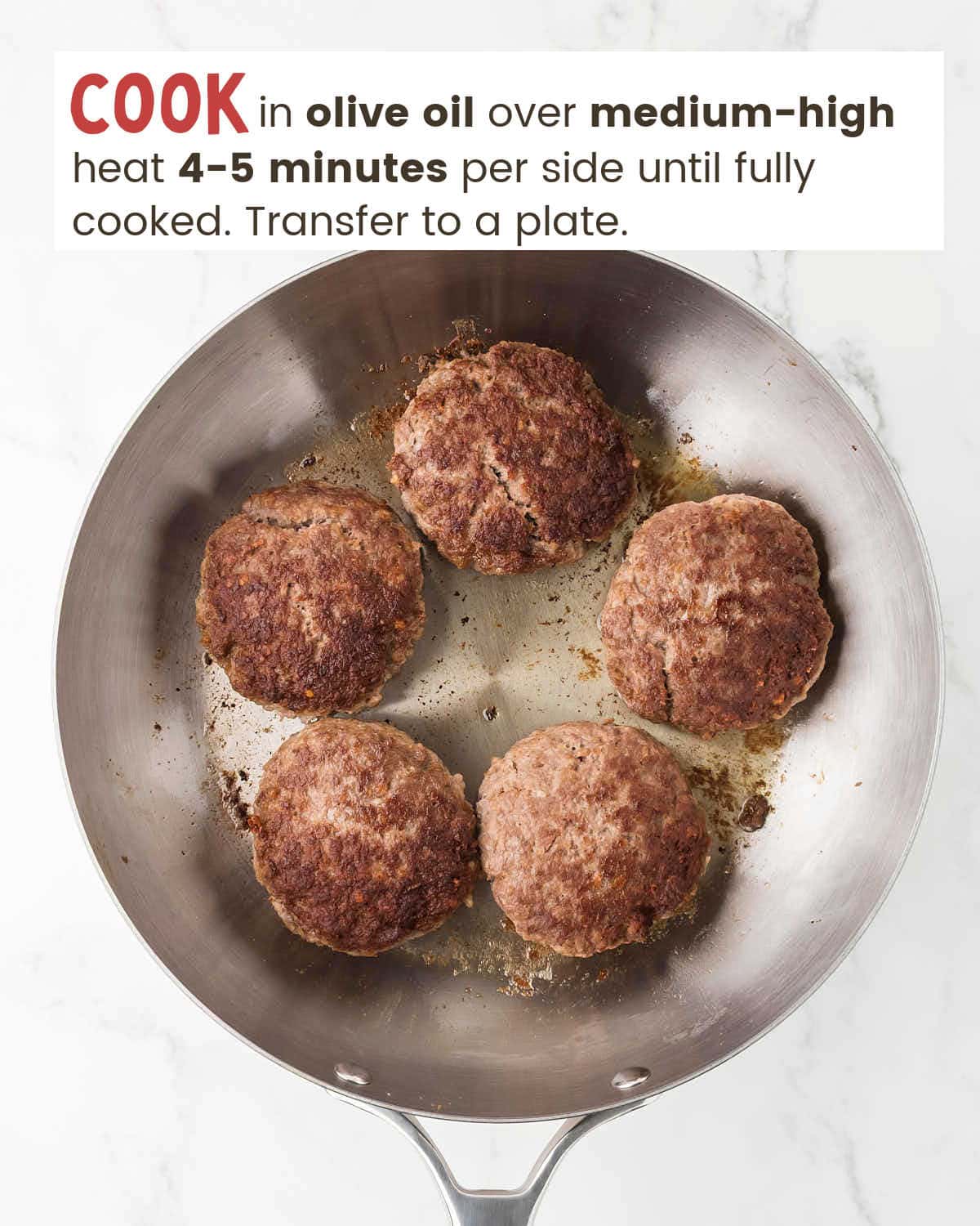 Ground beef patties in olive oil in a skillet.