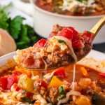A spoonful of Stuffed Pepper Soup with ground beef, rice, peppers, and melted cheese being lifted from a bowl.