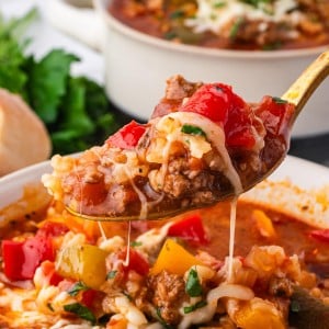 A spoonful of Stuffed Pepper Soup with ground beef, rice, peppers, and melted cheese being lifted from a bowl.