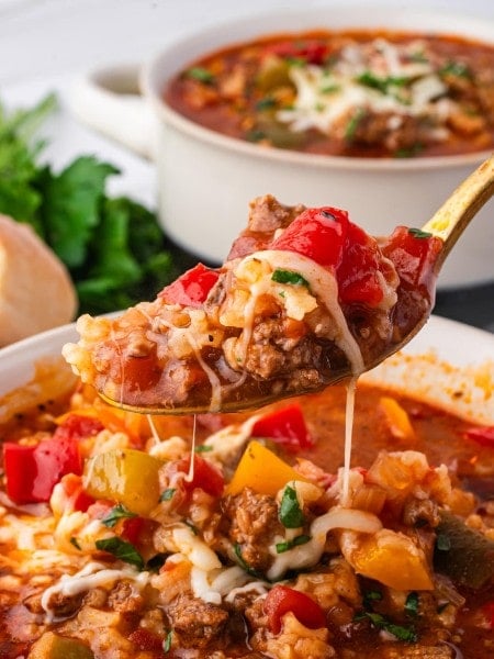 A spoonful of Stuffed Pepper Soup with ground beef, rice, peppers, and melted cheese being lifted from a bowl.