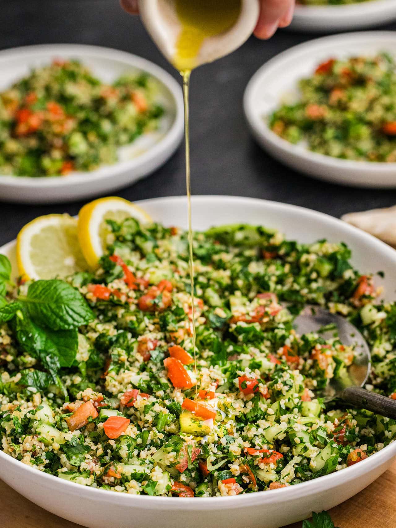 Pouring extra dressing into a bowl of Tabouli.