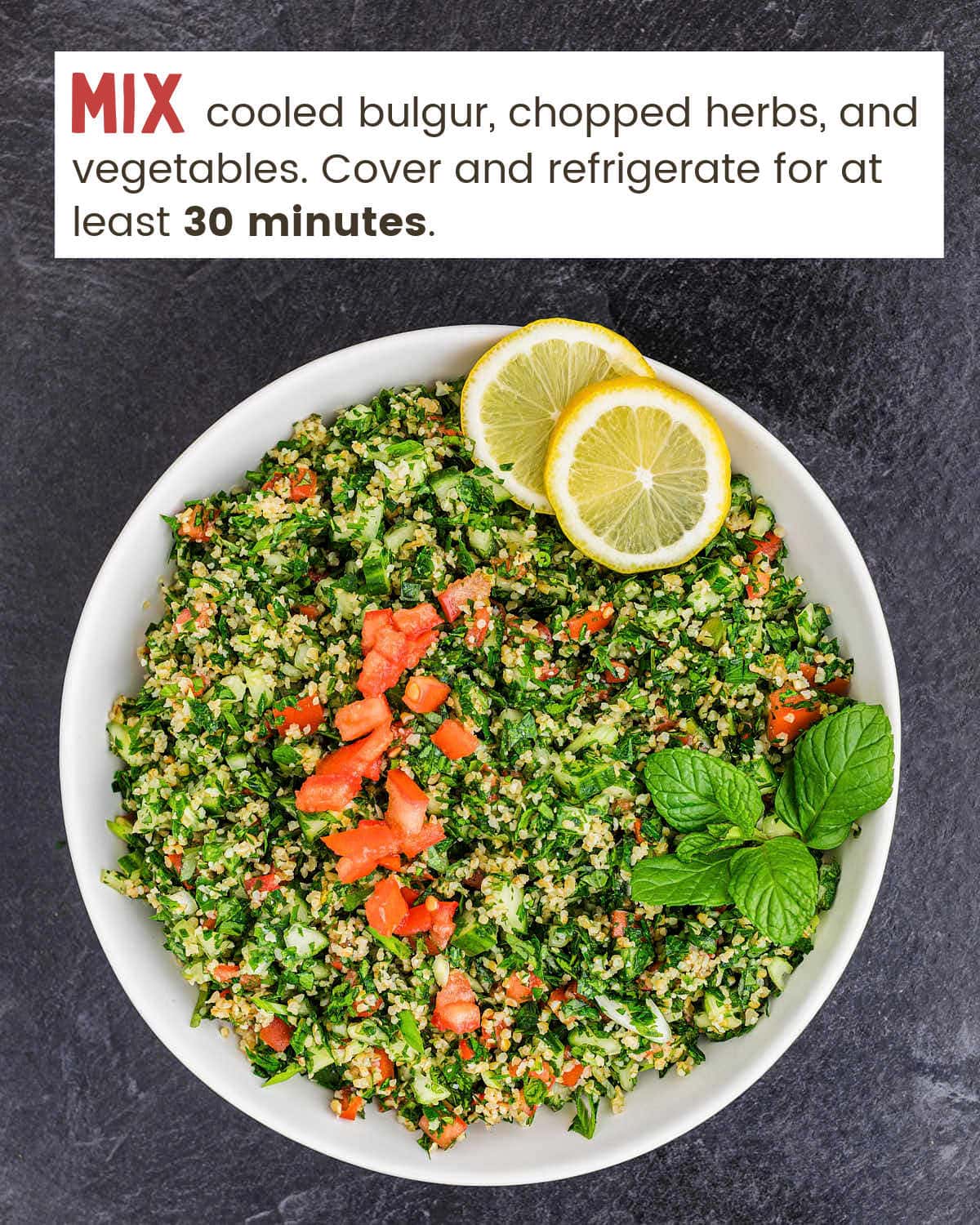 Tabouli with two lemon slices in a white bowl.