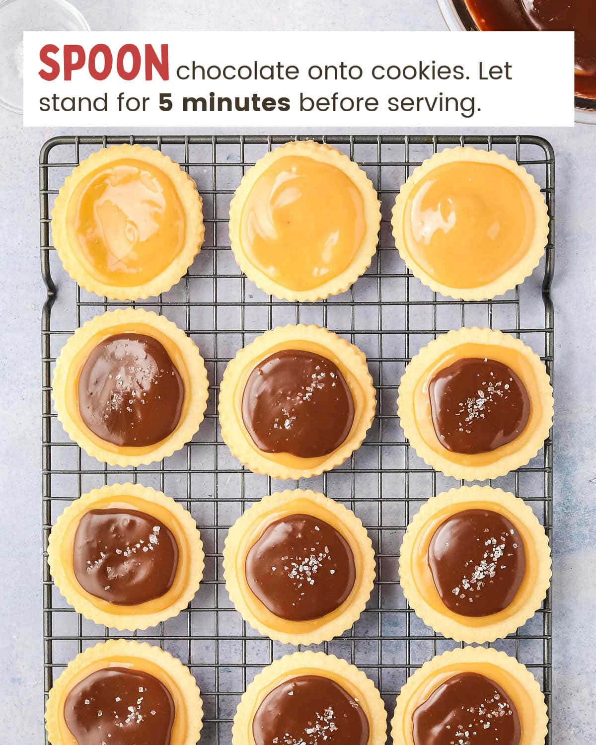 Chocolate over caramel on round cookies on a cooling rack.