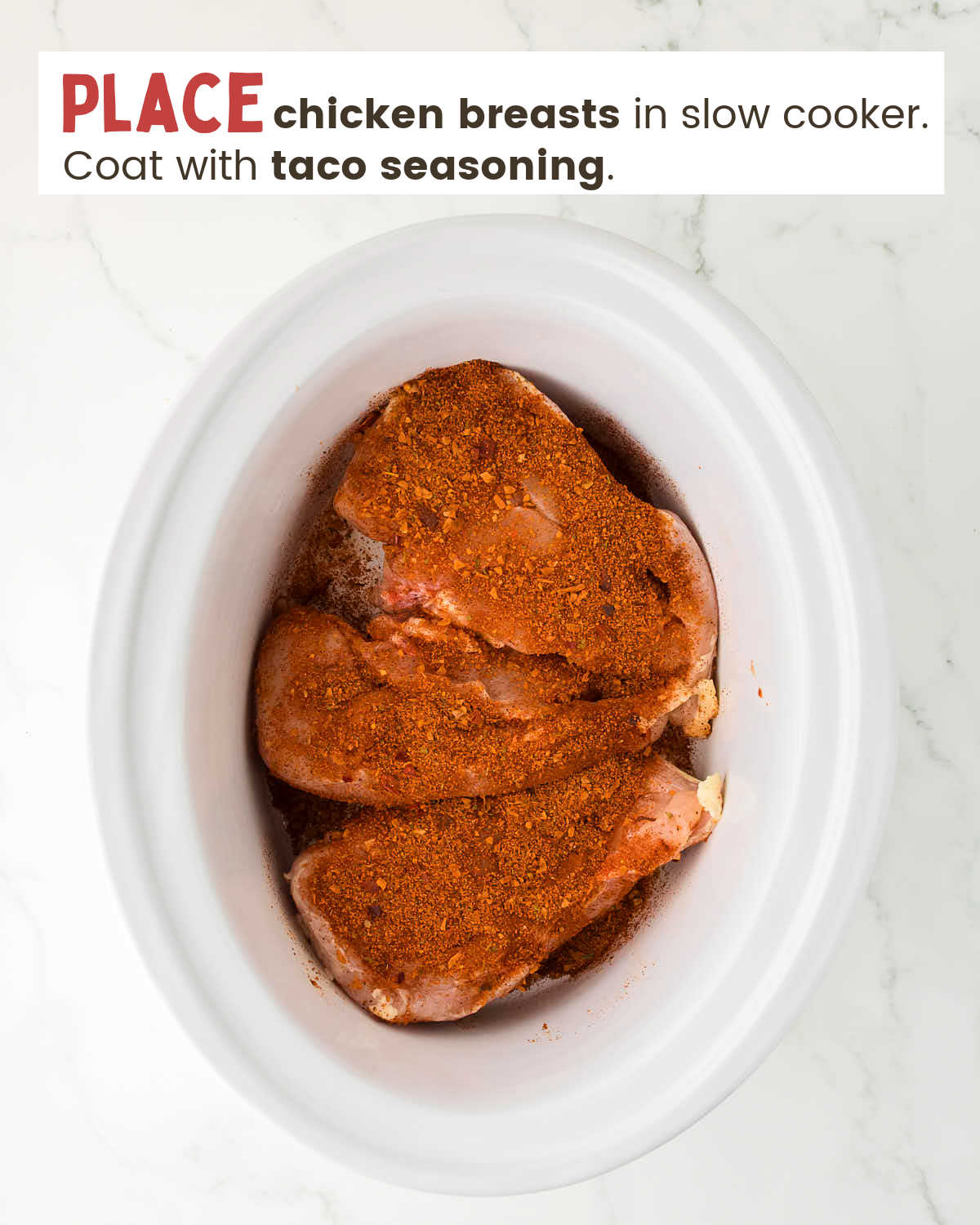 Chicken breasts topped with taco seasoning in a slow cooker.