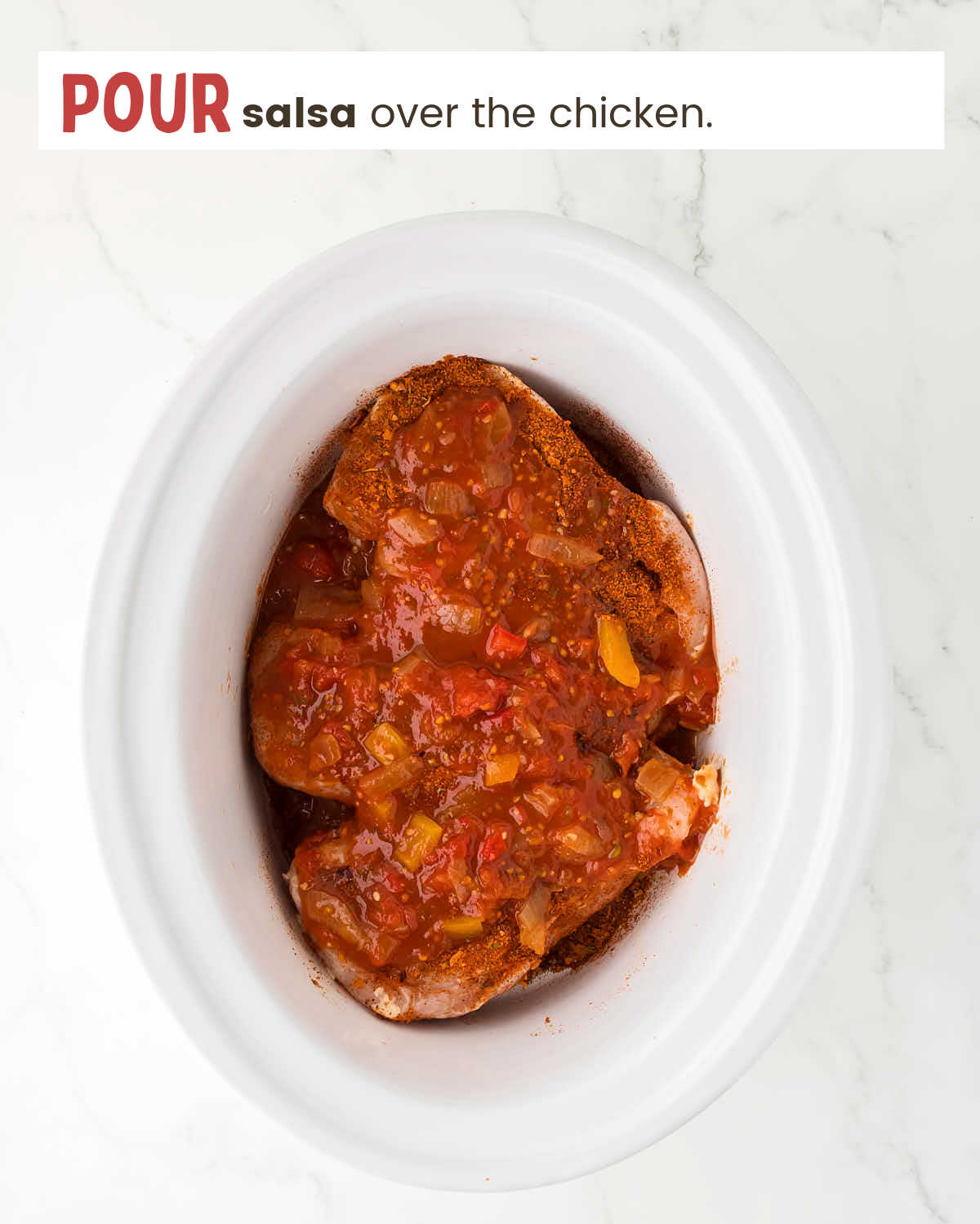 Chicken breasts topped with taco seasoning and salsa in a slow cooker.