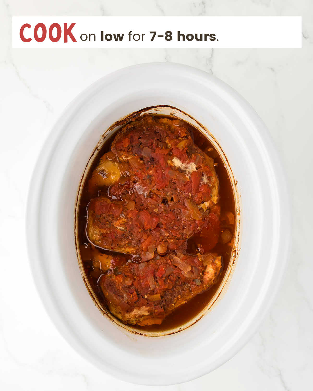 Cooked chicken breasts topped with taco seasoning and salsa in a slow cooker.
