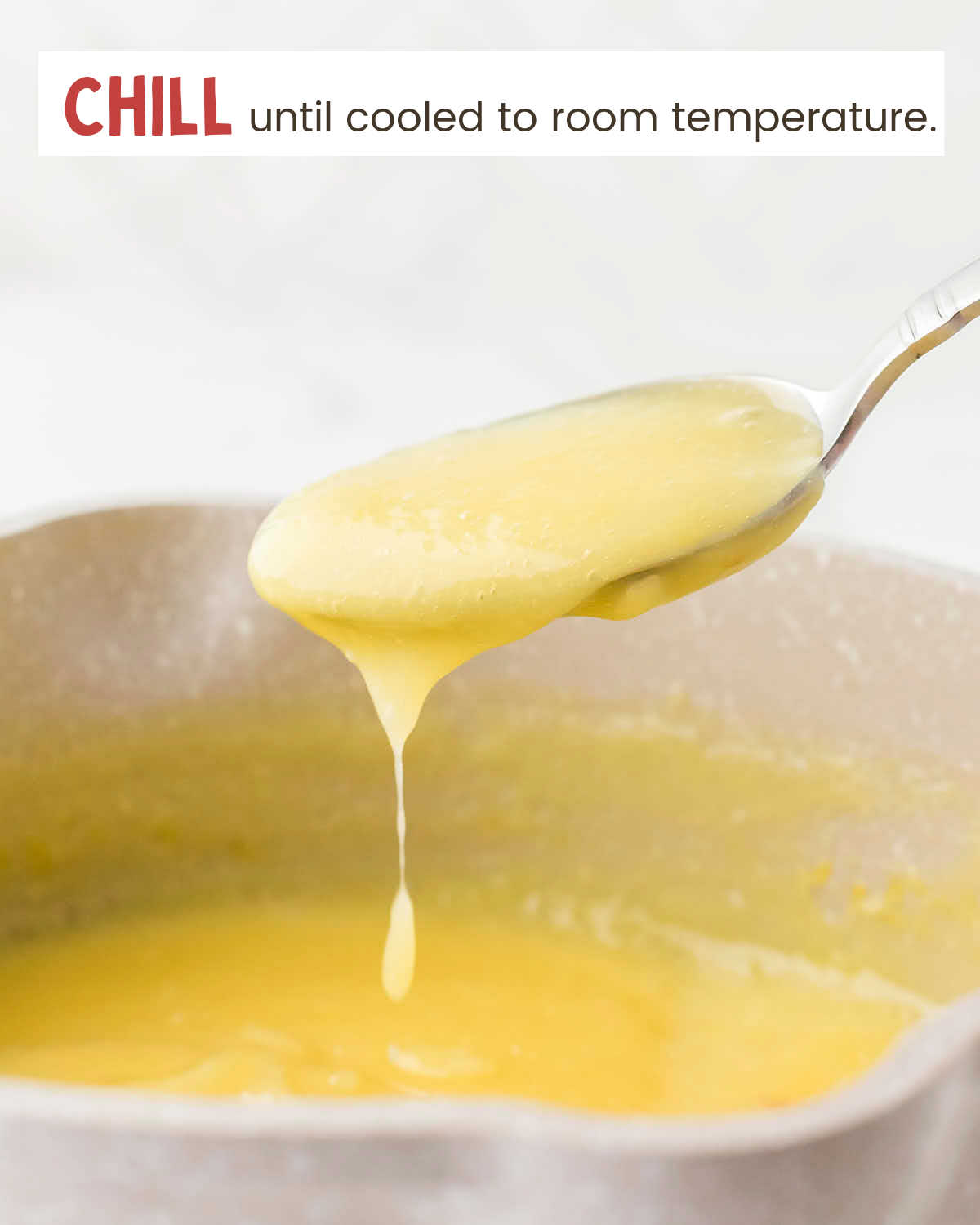 A spoon with custard over a saucepan with custard.