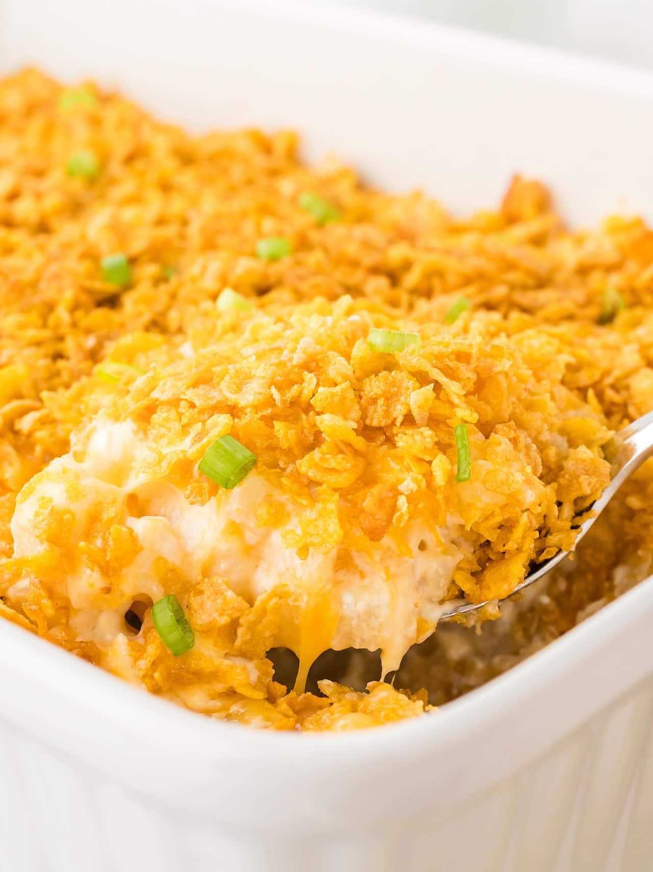 Lifting a serving spoon filled of Funeral Potatoes.