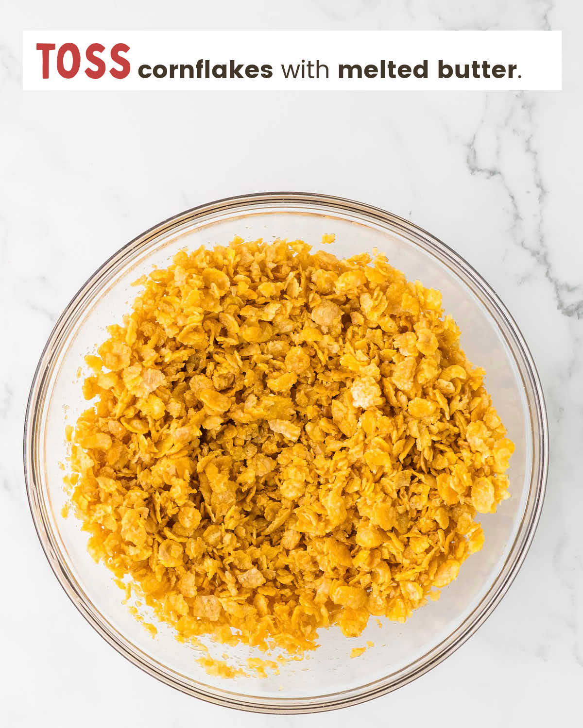 Cornflakes mixed with melted butter in bowl.