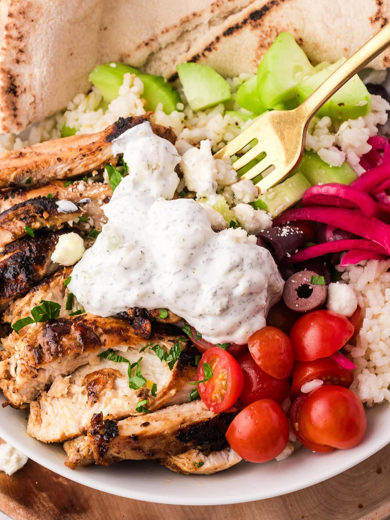A fork digging into a Greek Chicken Bowl.