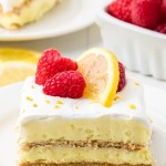 Lemon Icebox Cake topped with raspberries and lemon slices on a white plate.