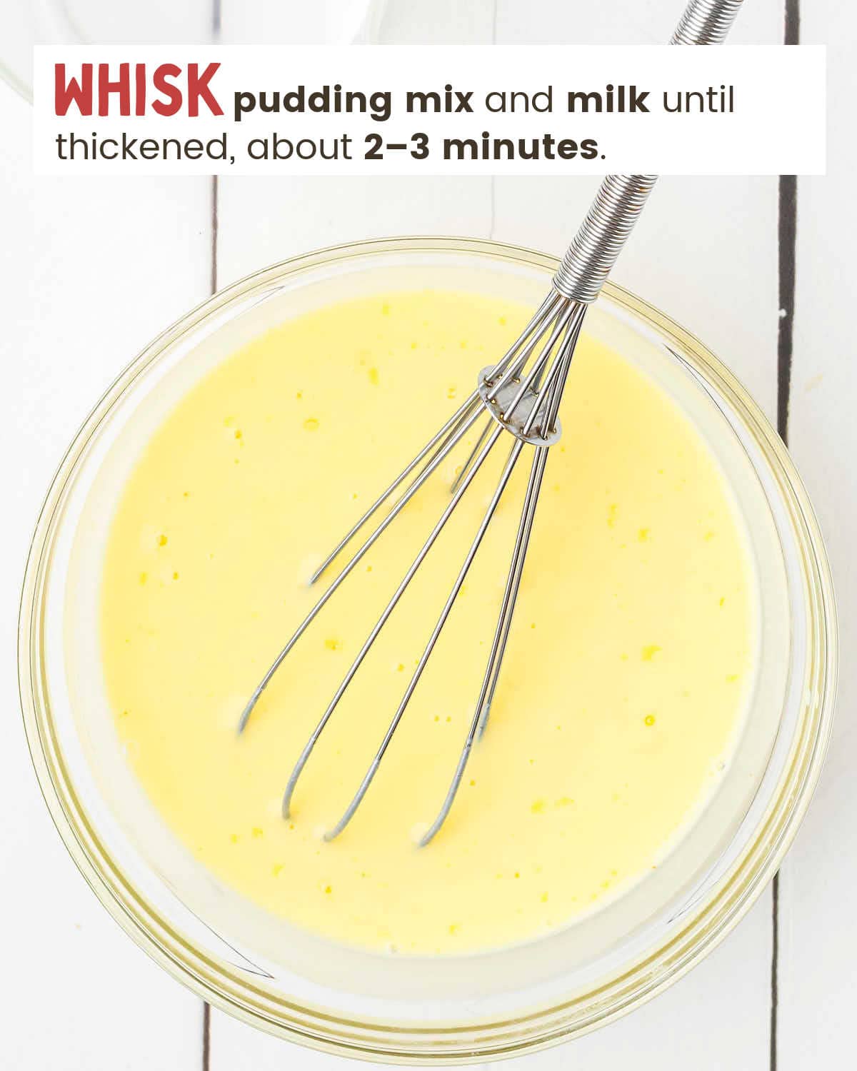 Lemon pudding mix and milk in a bowl with a whisk. 