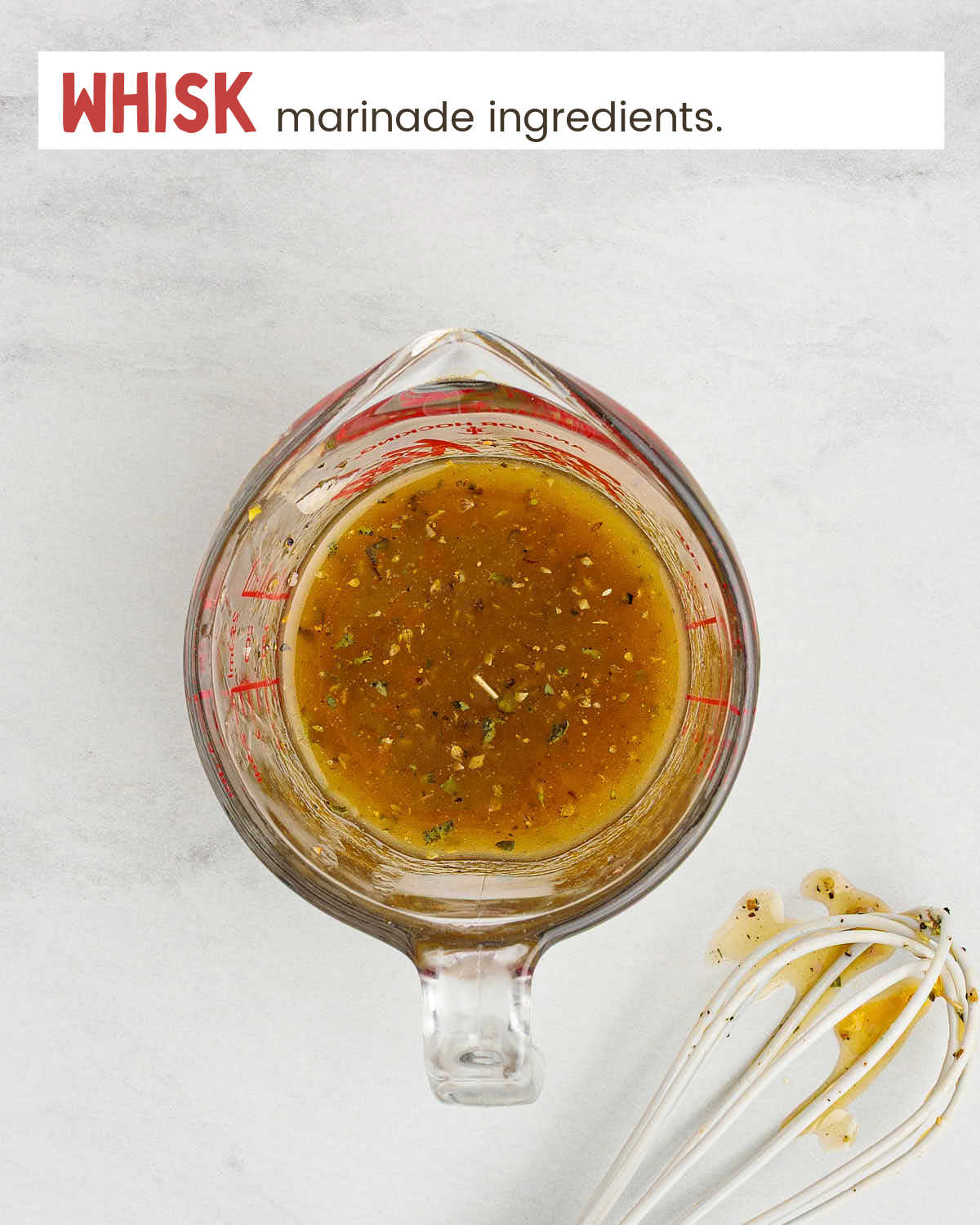 Marinade in a glass measuring cup with a whisk nearby. 