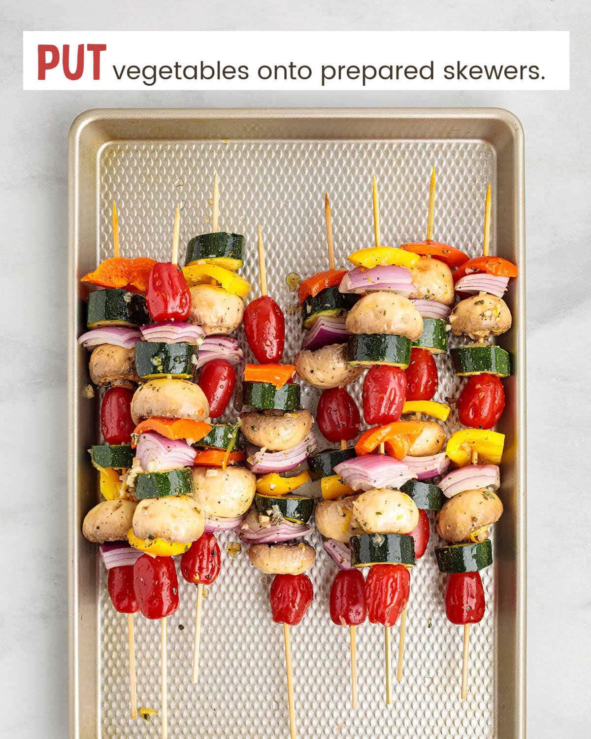 Veggie chunks on wooden skewers on a baking tray.