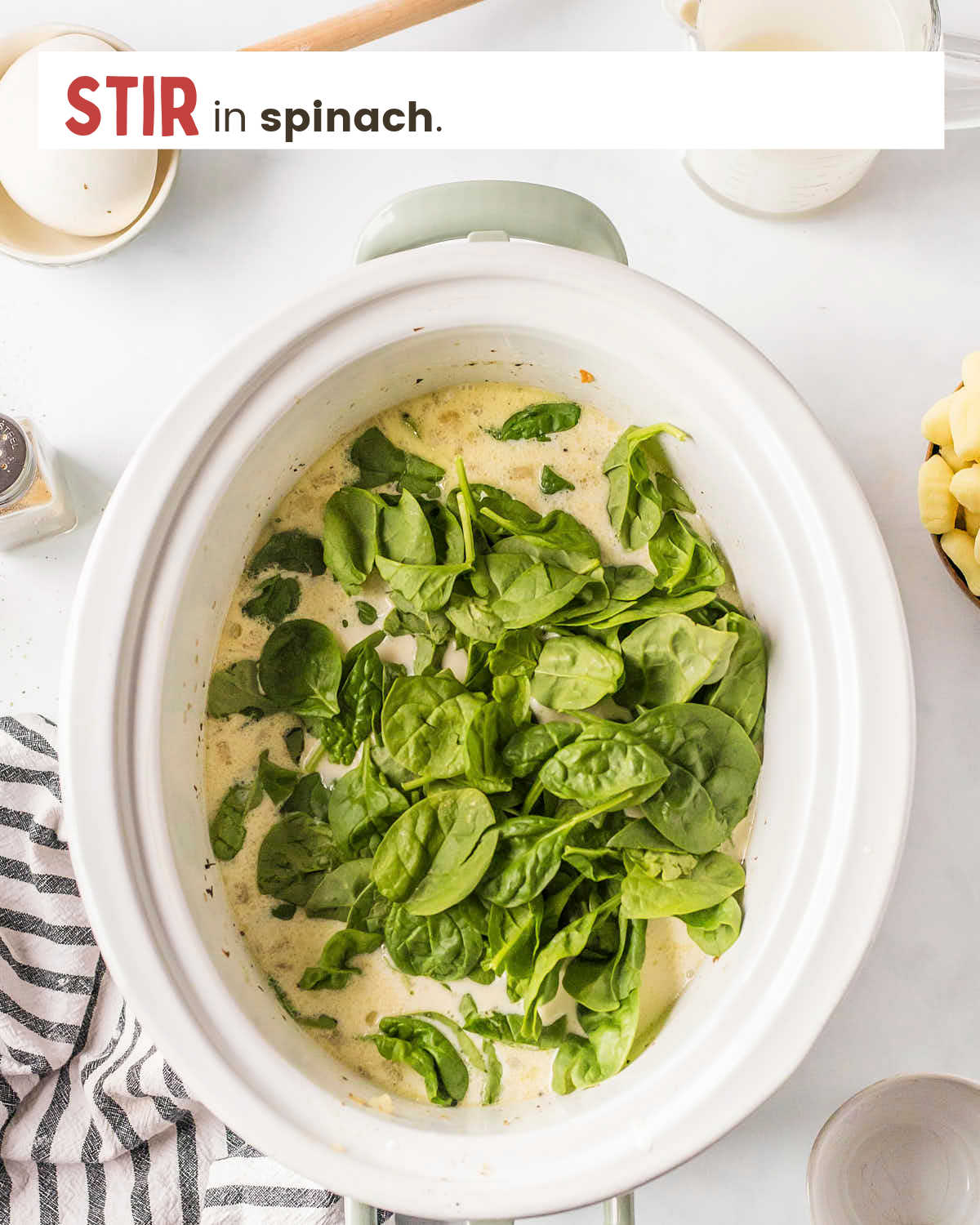 Spinach on top of soup in a large slow cooker.