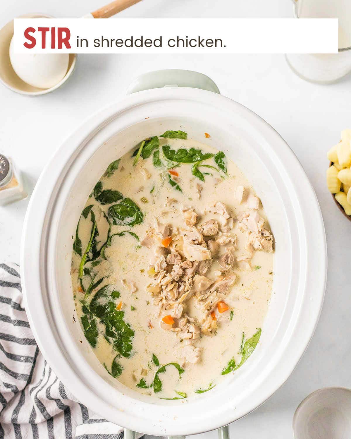 Chicken on top of soup in a large slow cooker.