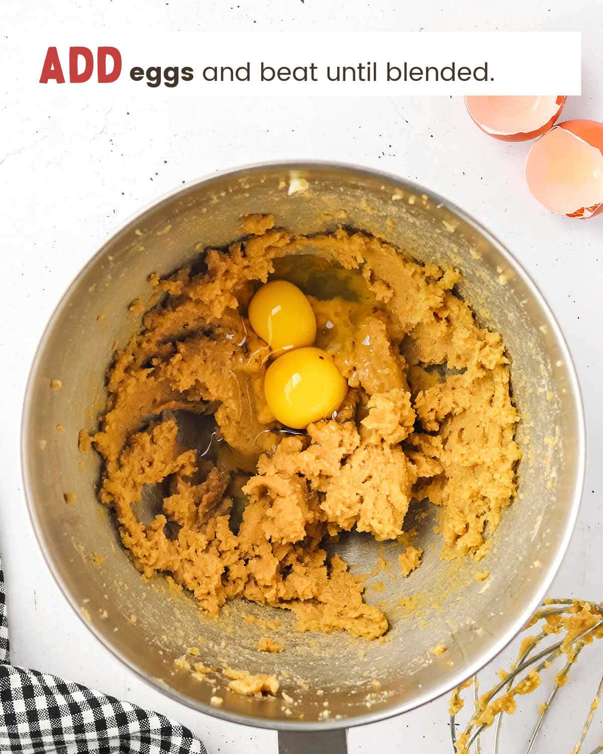 Cookie batter with two eggs on top in a metal mixing bowl.