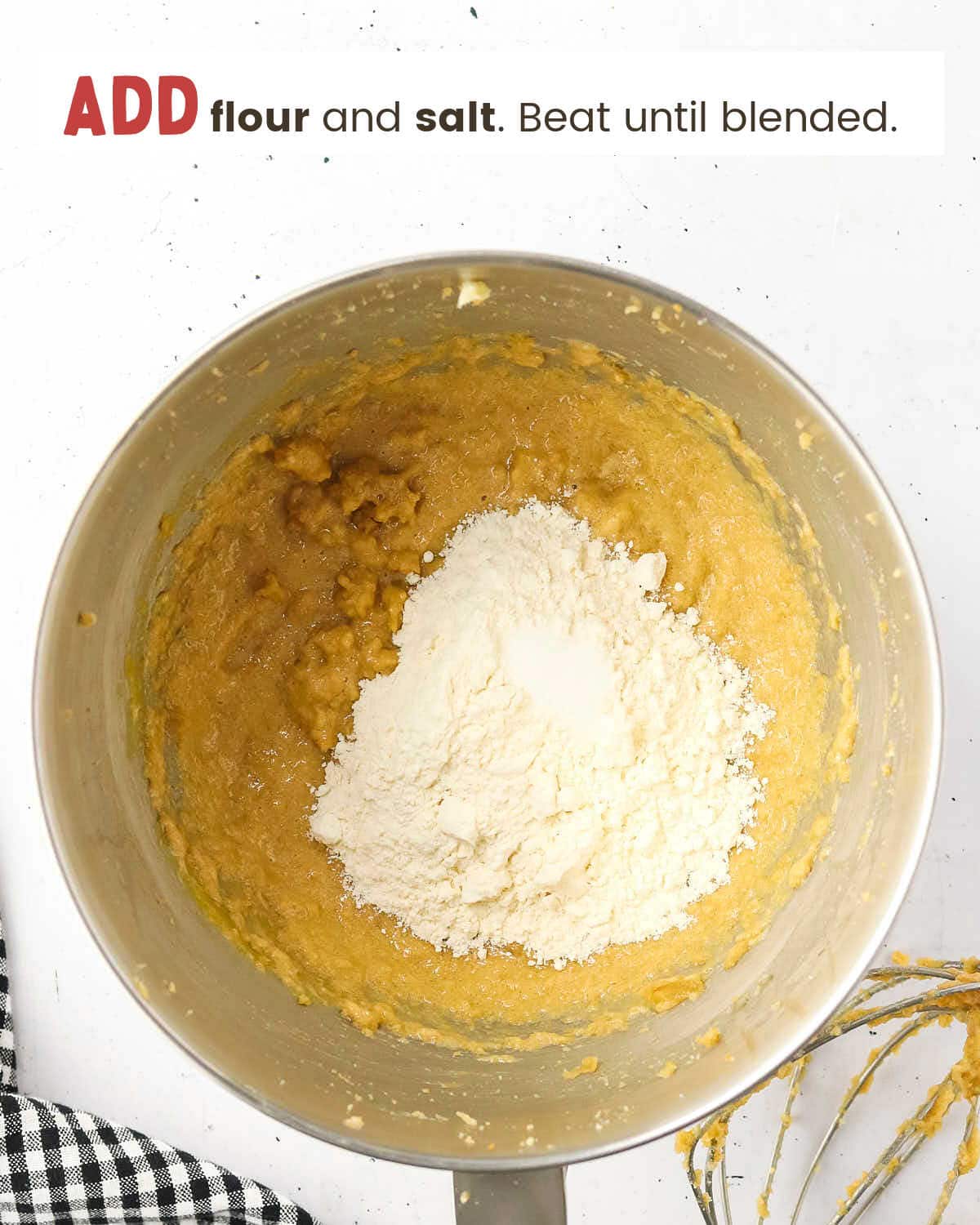 Cookie batter with flour and salt on top in a metal mixing bowl.