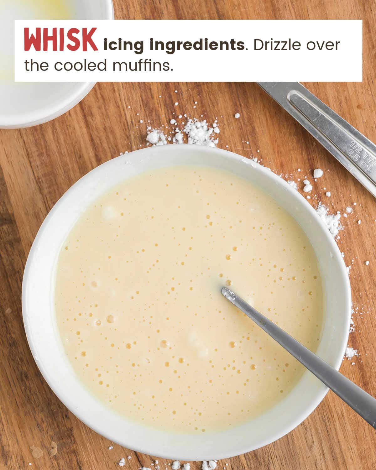 A spoon in a bowl of icing.