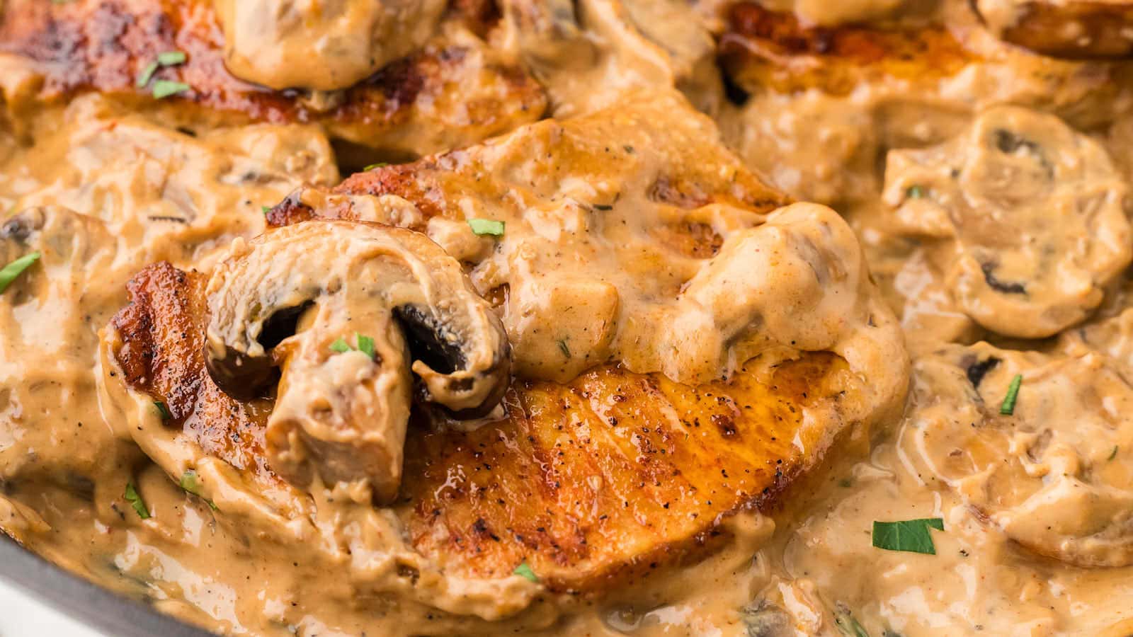 Closeup of a cream of mushroom pork chop in a cast iron skillet. 