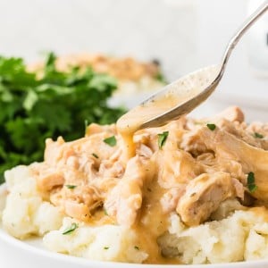 Drizzling gravy over Crockpot Chicken and Gravy served over mashed potatoes.