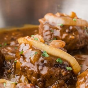 Hamburger Steak in a stainless steel skillet.