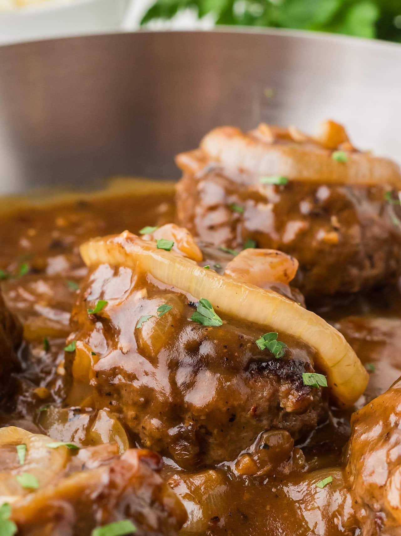 Hamburger Steak in a stainless steel skillet.