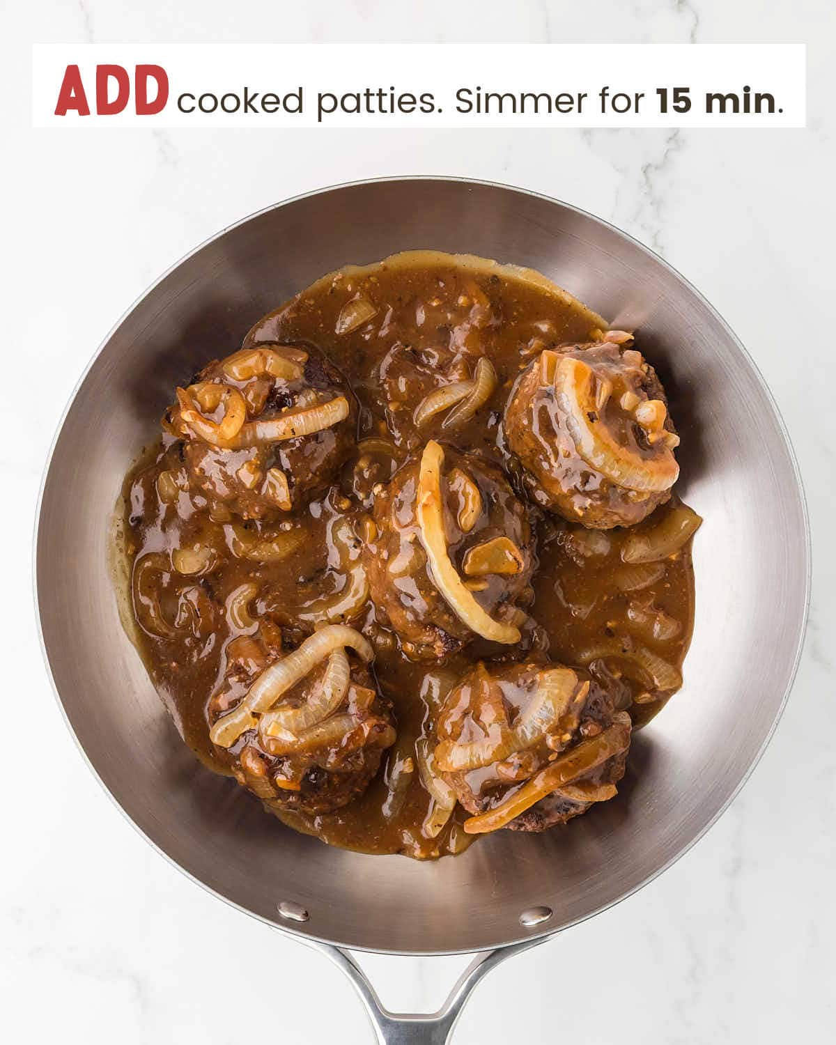 Gravy and onions over beef patties in a skillet.