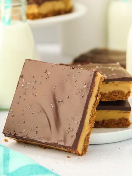 A slice of Millionaire Shortbread leaning against a white plate.