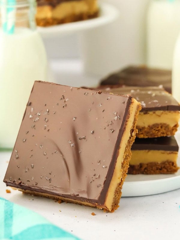 A slice of Millionaire Shortbread leaning against a white plate.