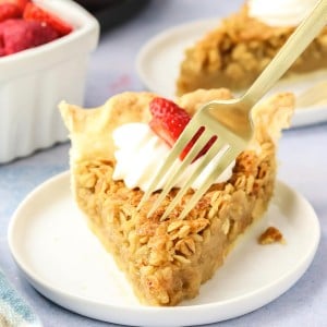 A fork digging into an Oatmeal Pie topped with whipped cream and strawberry.
