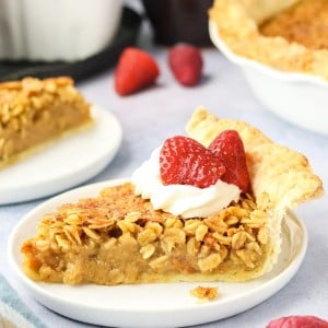 A slice of Oatmeal Pie with whipped cream and strawberries on a white plate.