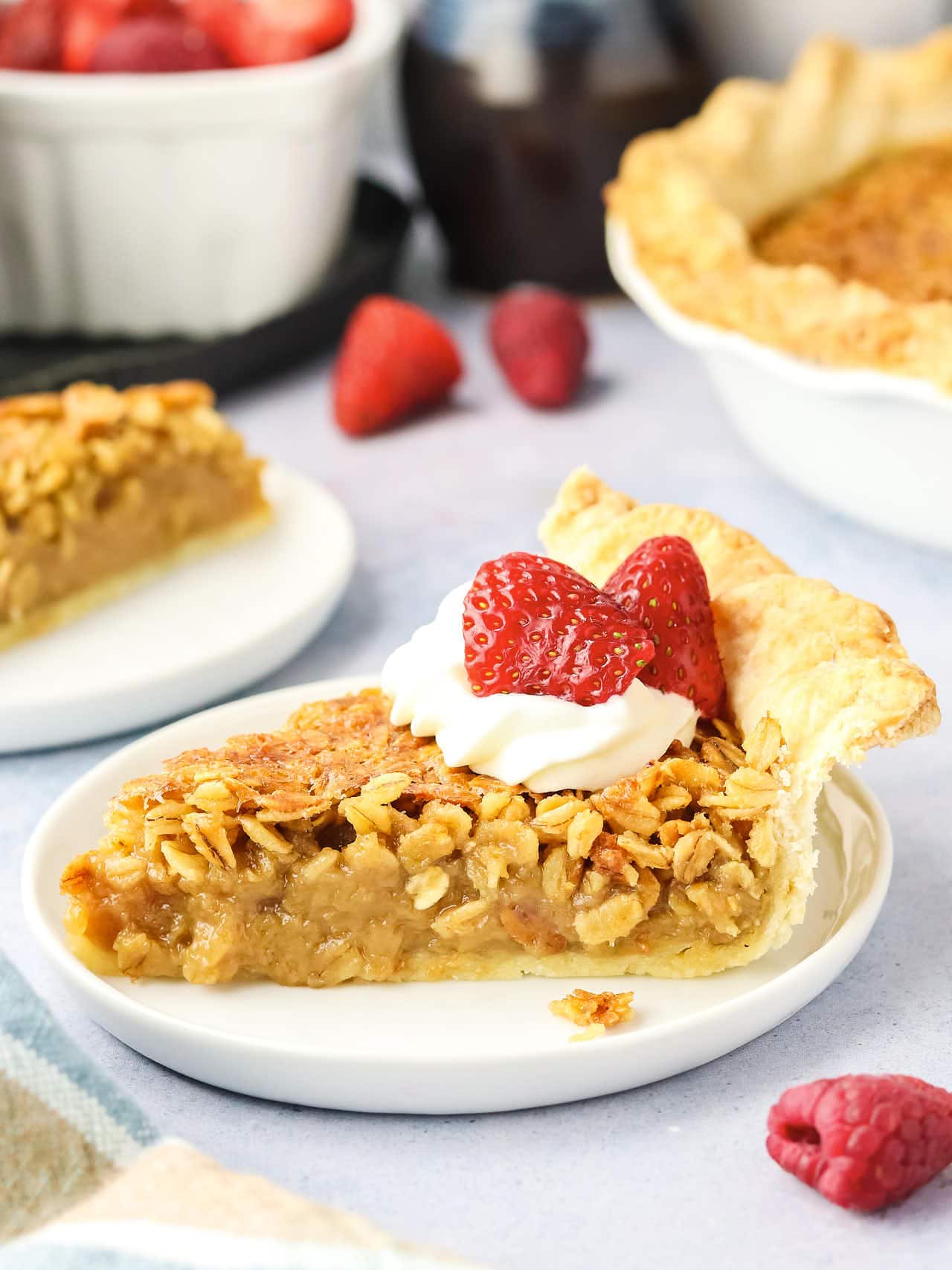 A slice of Oatmeal Pie with whipped cream and strawberries on a white plate.