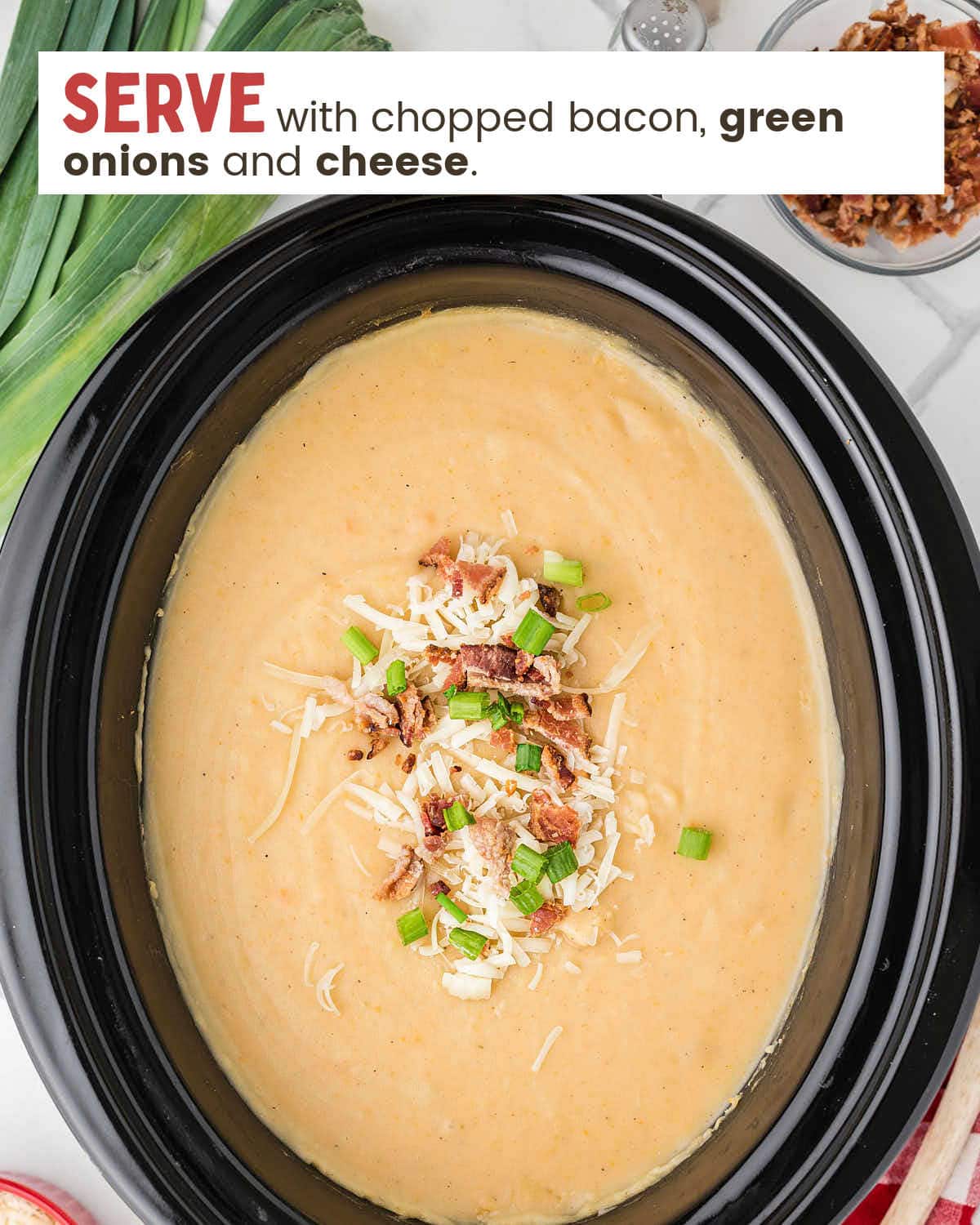 Potato and leek soup in a slow cooker topped with bacon bits, cheese, and green onions.
