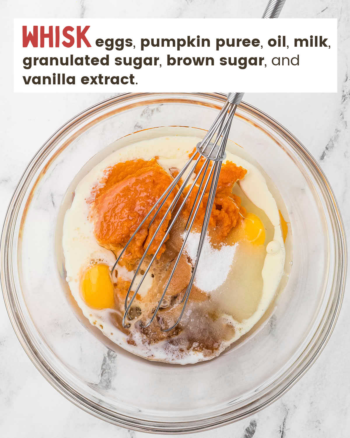 A whisk in pumpkin muffin ingredients in a glass bowl. 