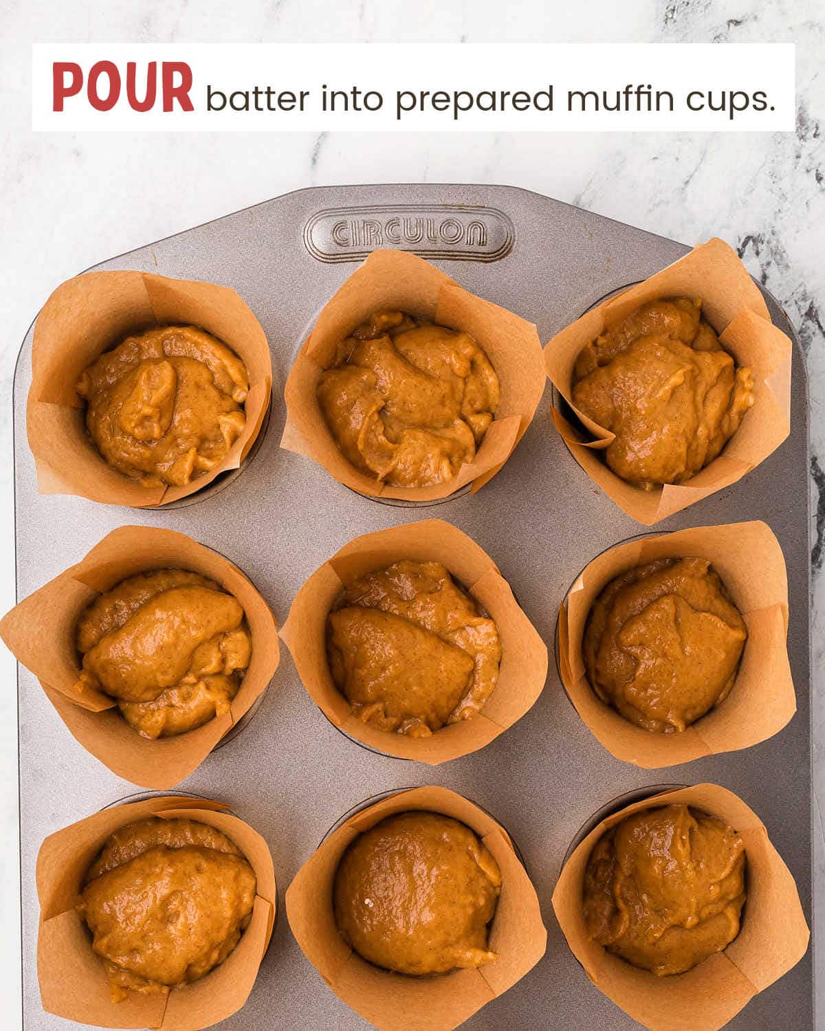 Pumpkin muffin batter in muffin tin cups lined with parchment paper.
