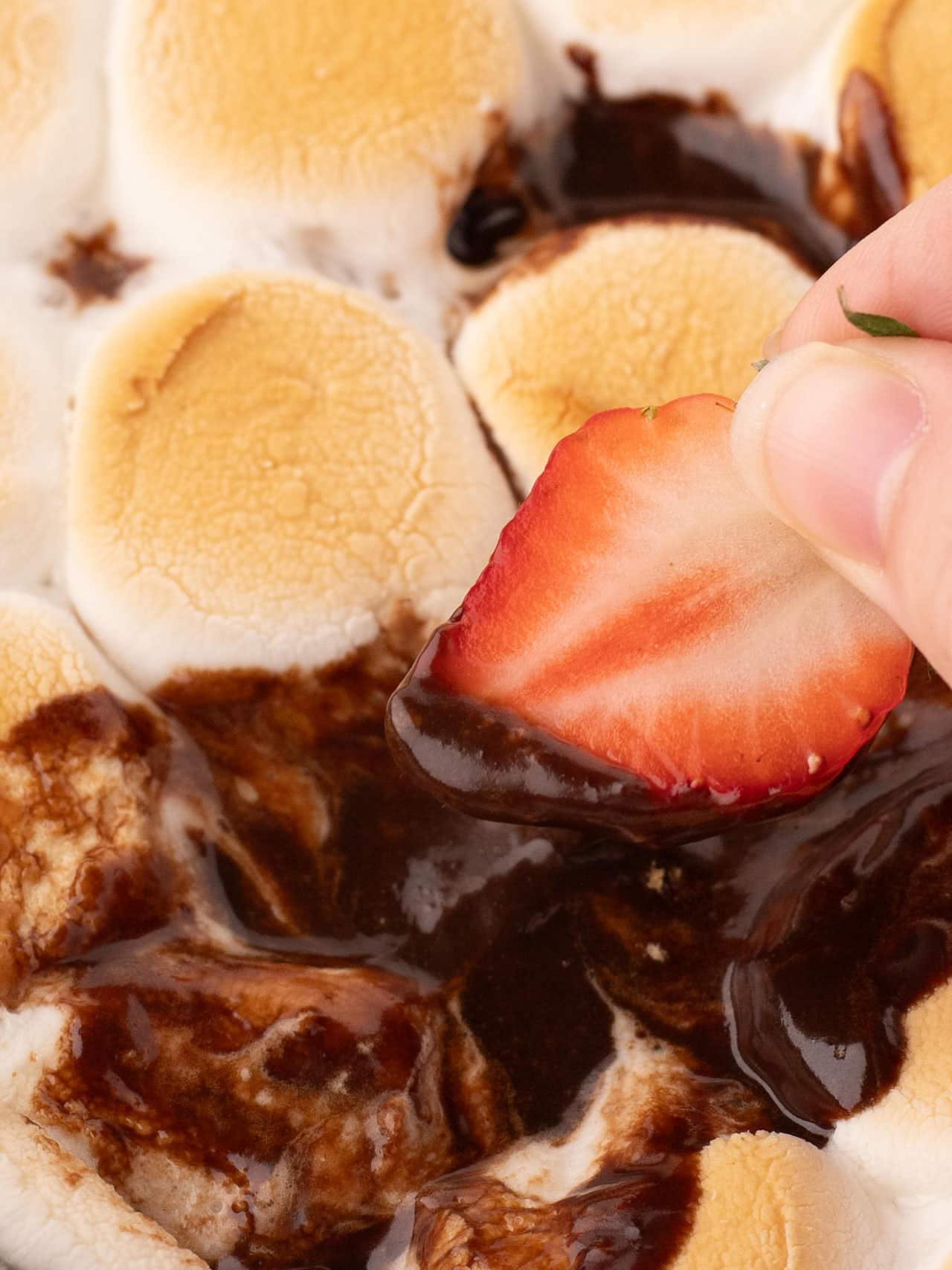 Scooping the S'mores Dip with a strawberry.