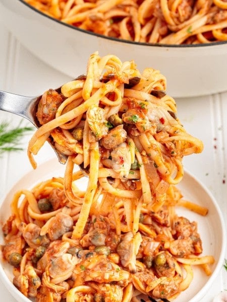 A serving spoon full of Linguini with Clams.